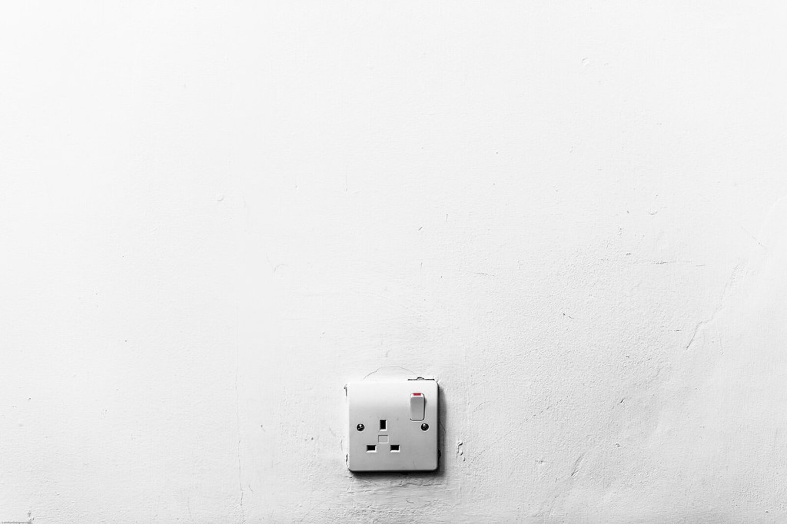A white UK double socket set low on a plain white wall