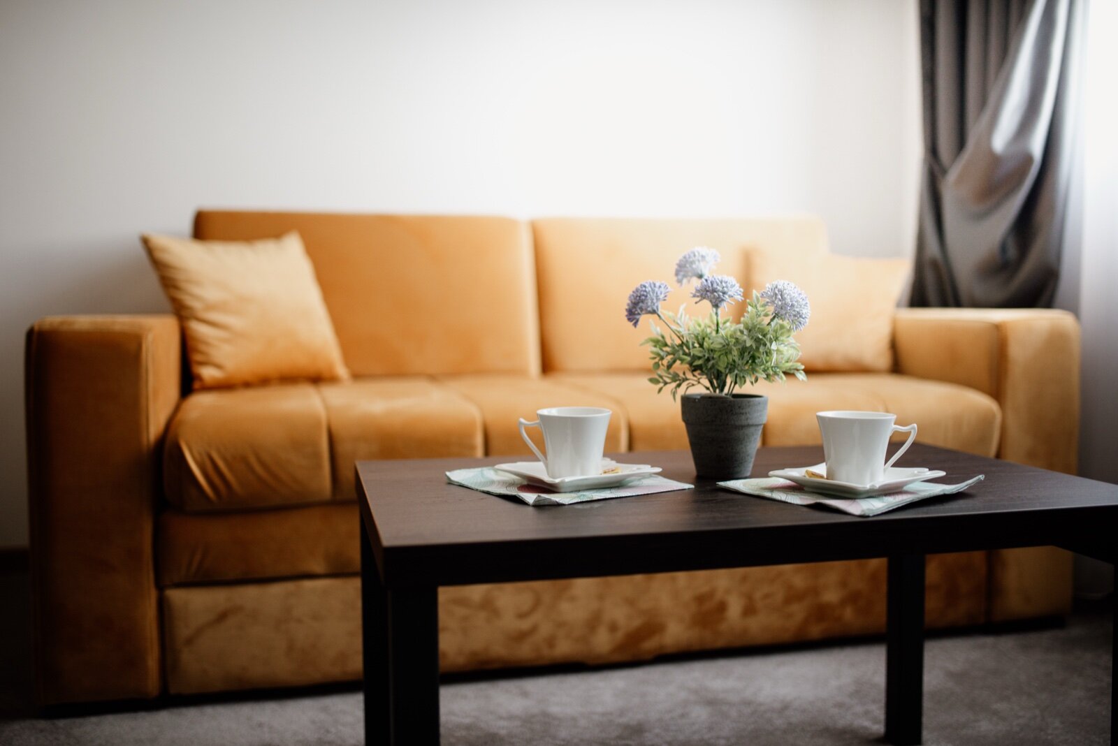 A warm-toned living room with an amber velvet sofa and a dark coffee table
